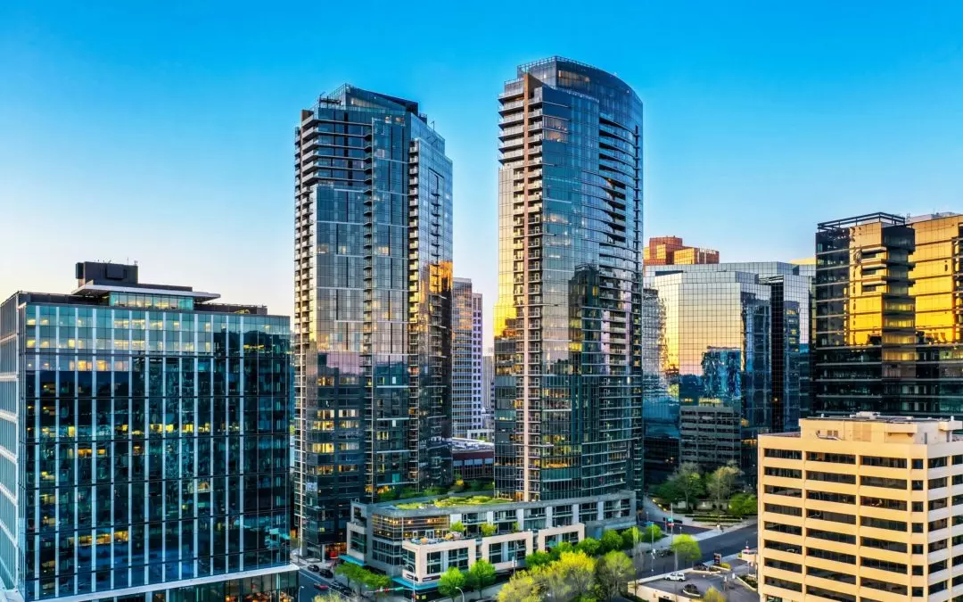 Row of modern glass skyscrapers reflecting sunlight against a bright blue sky.